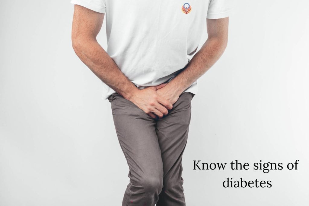 man in white tshirt with hands near groin, needing to use the washroom