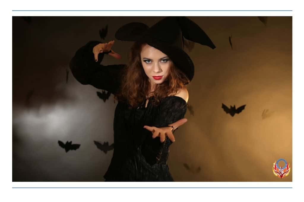 woman in witch costume with bats flying around behind her.